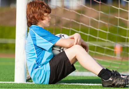 child leaning against a goal post