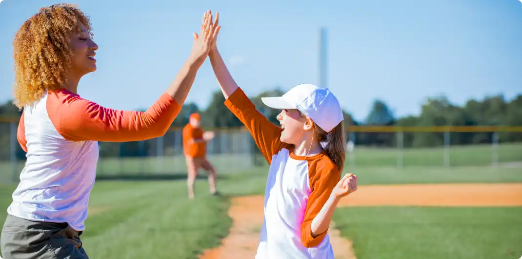 Photo of a female baseball coach high five one of her youth athlete